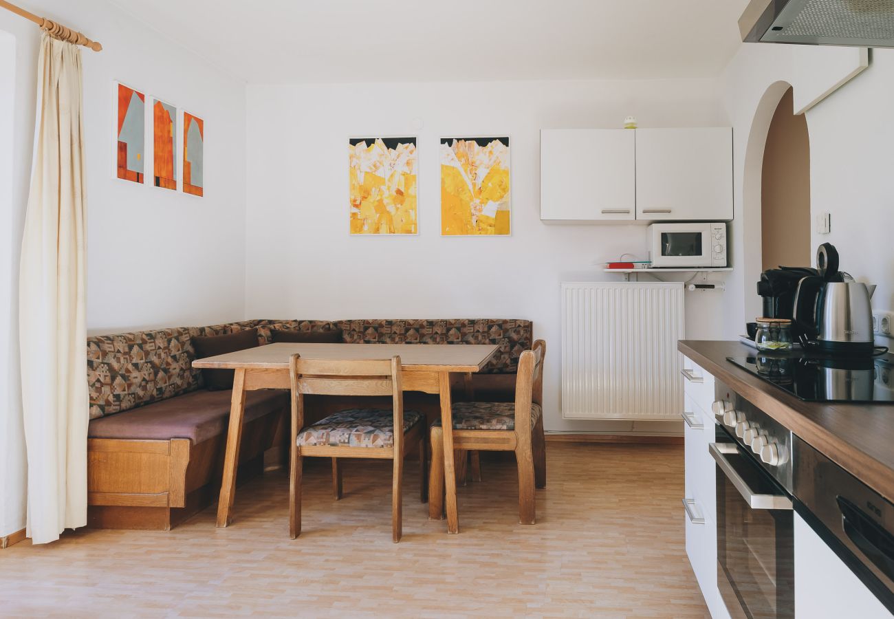 Living area in Apartments Haus Altenberger by we rent. Dining table, and kitchen with stove and oven.