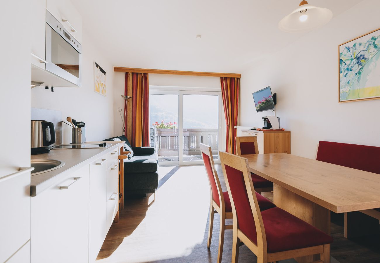 Dining room in the holiday apartment Apartments Haus Altenberger by we rent. Dining table, kitchen, living room, and balcony.